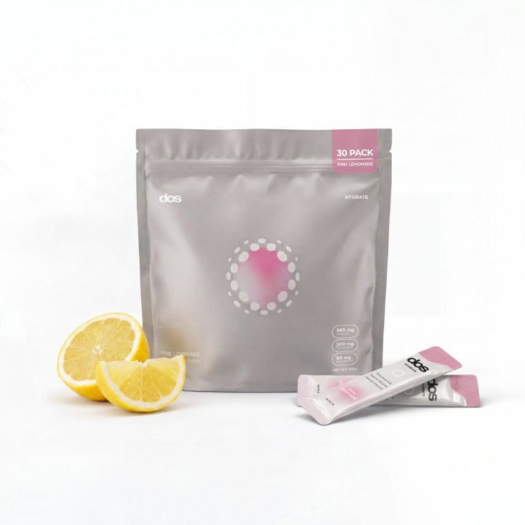 A dos Pink Lemonade 30 pack beside two fresh lemon halves and two sticks