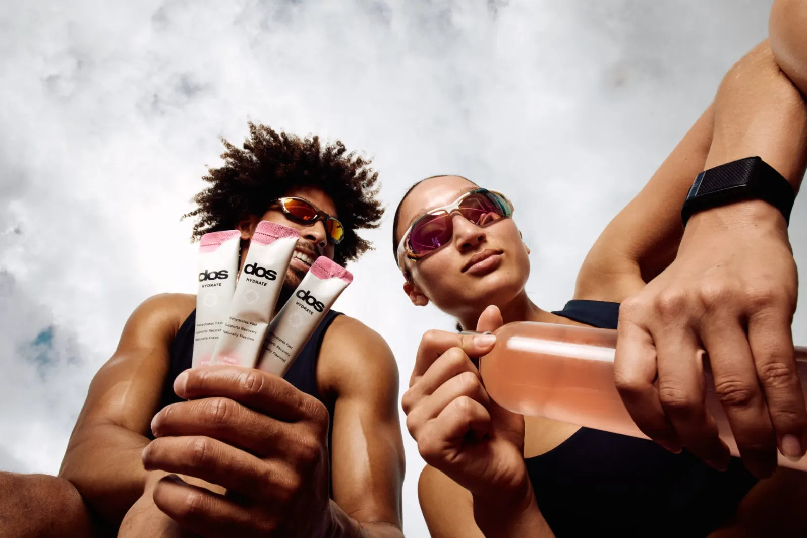 Two athletes with dos hydration sticks against a bright sky